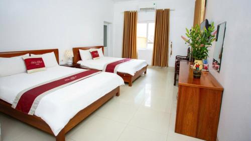 a hotel room with two beds and a table with flowers at Hòa Bình Tam Đảo Hotel in Tam Ðảo