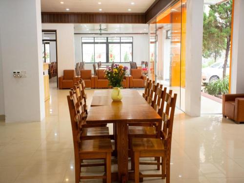 a wooden table with chairs and a vase of flowers on it at Hòa Bình Tam Đảo Hotel in Tam Ðảo