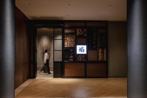 a person walking into a building with a sign on the door at New World Guangzhou Hotel-- FREE Canton Fair Shuttle Bus in Guangzhou