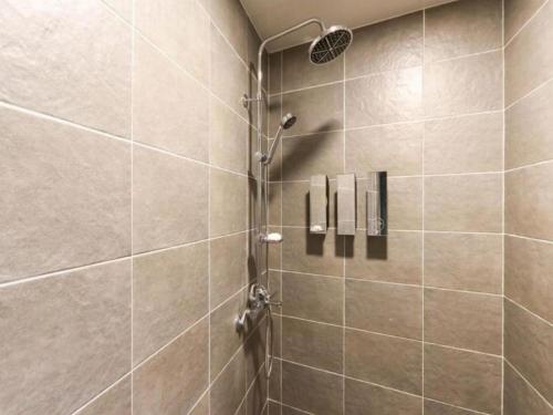 une douche avec pommeau de douche dans une salle de bain dans l'établissement Nampo Foxy Hotel, à Busan
