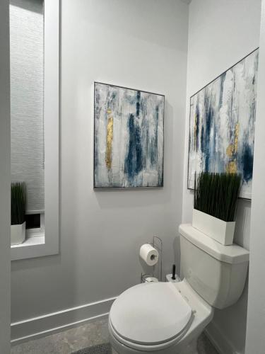 a bathroom with a toilet with two paintings on the wall at French Style Mansion In Prestigious Angus Glen Markham in Markham