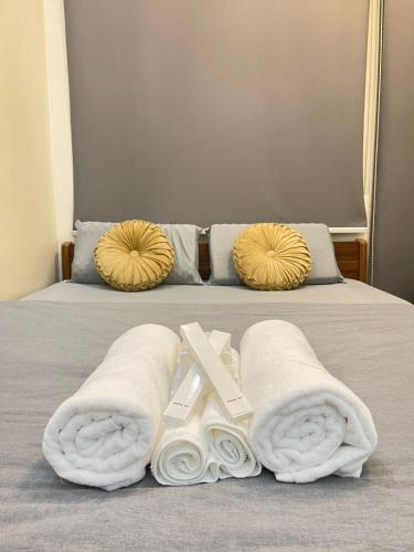 a bed with two towels and two pillows on it at Orchids Shore Residences Direct Pool Access in Manila