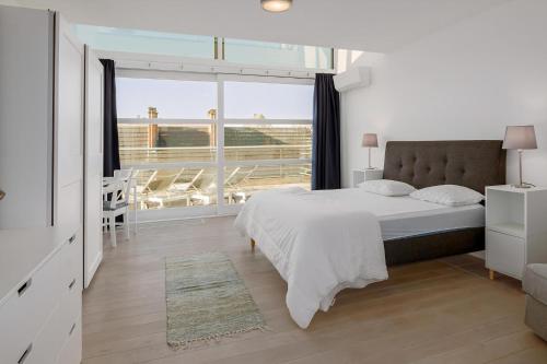 Un dormitorio blanco con una cama y una ventana grande. en Nausicaa 0501 G, en Oostduinkerke