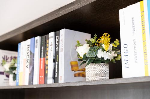 a book shelf with books and a vase with flowers at LZ Hotel in Chengdu