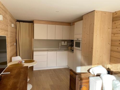 une cuisine avec des armoires blanches et une table dans une pièce dans l'établissement Appartement cosy avec Wi-Fi et parking privatif aux Gets - FR-1-671-288, aux Gets