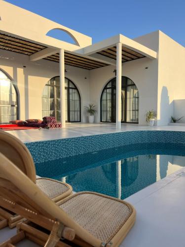 a swimming pool with a chair next to a house at zahr albun villa in Al Raka
