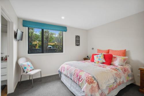 a bedroom with a bed and a window and a chair at Rangi Marie - Alexandra Holiday Home in Alexandra