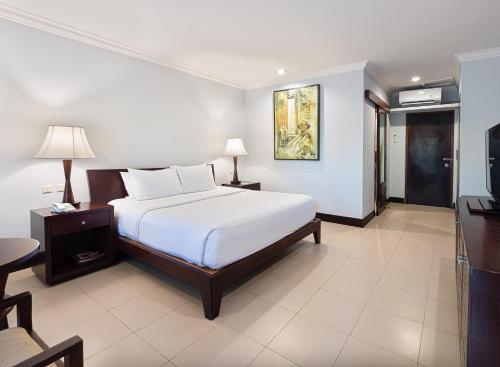 a bedroom with a white bed and a television at Puri Santrian Beach Resort And Spa in Sanur