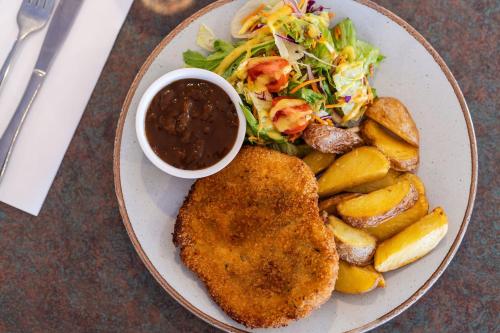 a plate of food with chicken and a salad and sauce at The Lodge Motel Newman in Newman