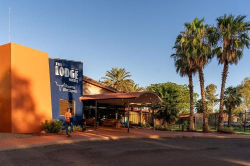 a person standing in front of a building with palm trees at The Lodge Motel Newman in Newman