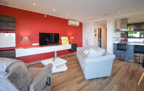Elle comprend un salon doté d'un mur rouge et d'une télévision. dans l'établissement 2 Bedroom Lovely Home In Cervione, à Cervione