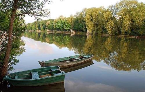 un bateau vert assis sur l'eau à côté des arbres dans l'établissement Maison Hortensias Avec Piscine, à Gien