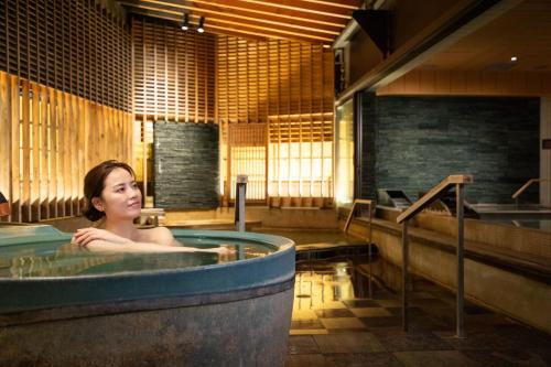 a woman sitting in a hot tub in a room at Hakodate Hotel Banso in Hakodate
