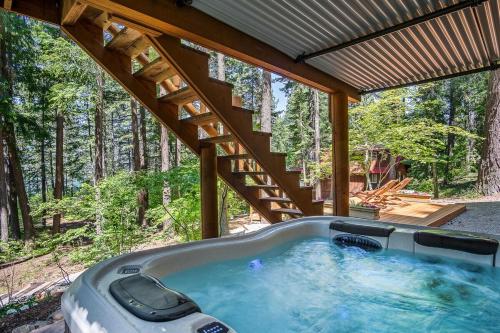 una bañera de hidromasaje bajo un techo en el bosque en Lakefront Log Cabin with Hot Tub, Huge Game Room and Direct Access to Cle Elum Lake, en Ronald