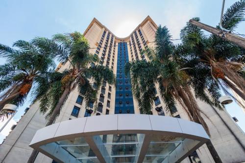a tall building with palm trees in front of it at LFlats no Hotel Aeroporto Congonhas in Sao Paulo