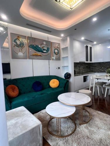 a living room with a green couch and two tables at Diamond Crown Hải Phòng in Ðông Khê