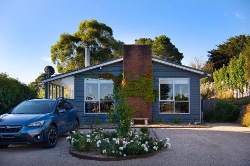 a blue house with a car parked in front of it at Indus- a bright and welcoming home in Daylesford