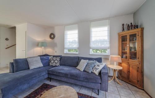 a living room with a blue couch and two windows at Stunning Home In Wemeldinge With Sauna in Wemeldinge