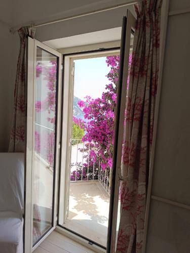 a sliding glass door leading to a balcony with purple flowers at Love in Blue - La Terrazza di Positano in Positano