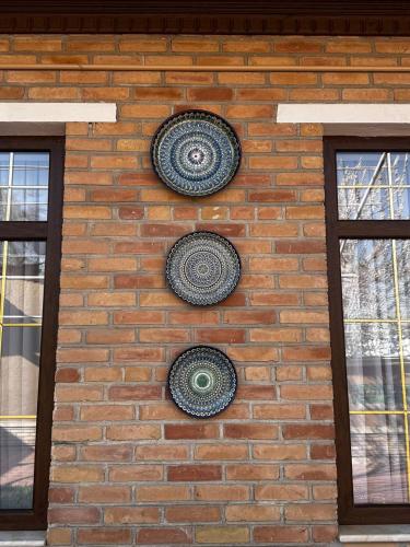 two plates on a brick wall with two windows at Salomat guest house in Samarkand