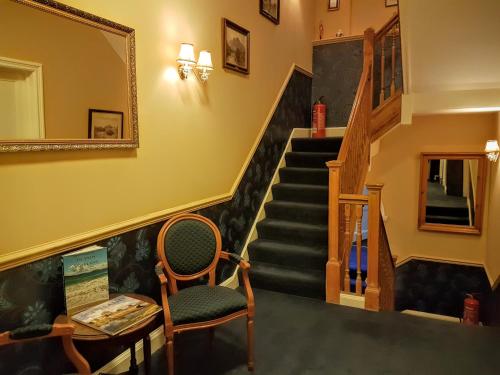 a room with a chair and stairs with a mirror at AmarAgua Guest house in Edinburgh