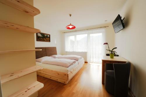 a bedroom with a bed and a desk and a television at Pension Sonnblick in Sankt Kanzian