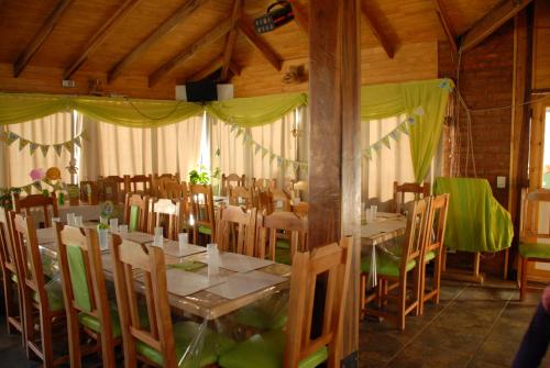 a dining room with tables and chairs with green drapes at Cabañas Rincones del Sur in Trevelin