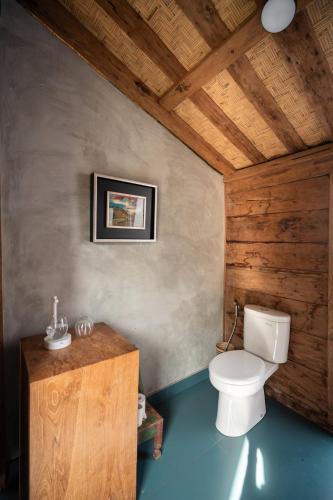 a bathroom with a toilet and a wooden ceiling at Desa Seni Baturiti in Baturiti