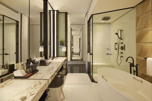 a bathroom with two sinks and a bath tub and a tub at Keraton At The Plaza, part of The Unbound Collection by Hyatt in Jakarta