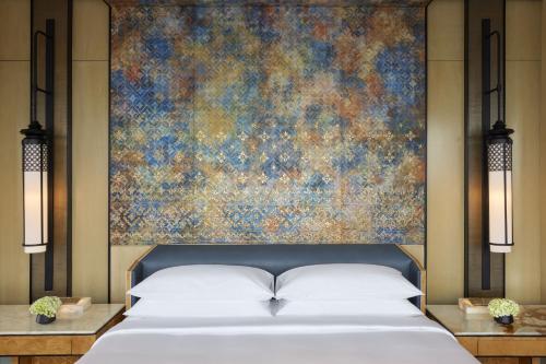 a bedroom with a bed with a painting on the wall at Keraton At The Plaza, part of The Unbound Collection by Hyatt in Jakarta