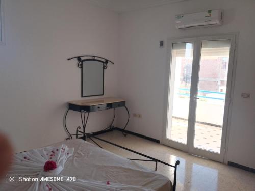 a bedroom with a bed and a mirror and a window at Villa mimosas avec piscine in Taguermess
