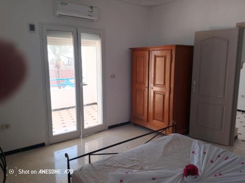 a bedroom with a bed and a door to a balcony at Villa mimosas avec piscine in Taguermess