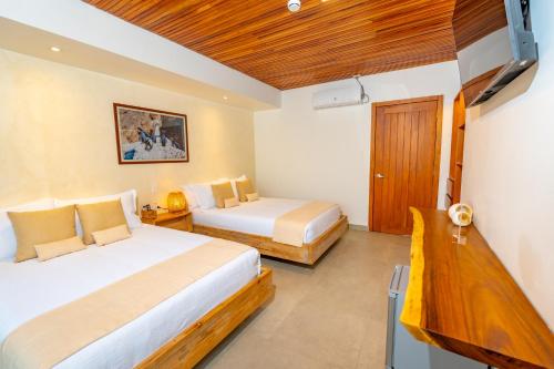 a bedroom with two beds and a wooden ceiling at El Barranco Galapagos in Puerto Ayora
