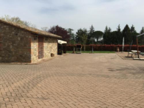 a brick courtyard with a building and a playground at Azienda Agrituristica I Tre Casali in Magione