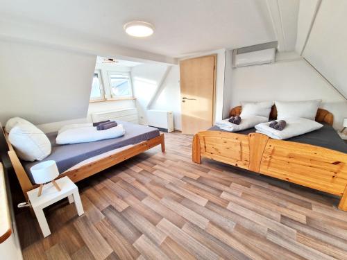 two beds in a small room with wooden floors at Superior Duplex Apartment - nur 5 min vom Europa-Park in Rheinhausen
