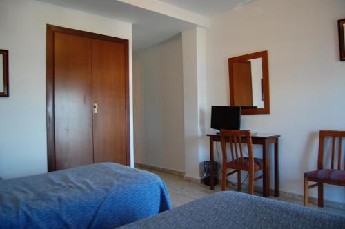a bedroom with a bed and a desk and a television at Hotel Marina Victoria in Algeciras