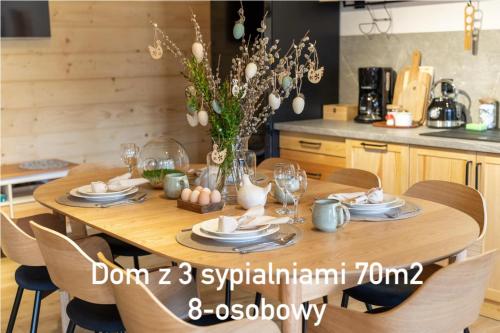 una mesa de madera con platos y gafas en la cocina en Nowe Domki Jeleni Szlak, en Ustrzyki Dolne