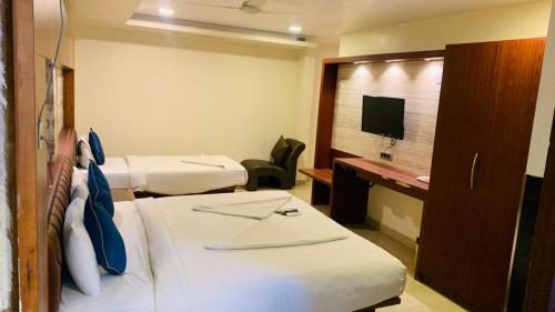 a hotel room with two beds and a television at Hotel Adya Classsic in Kammasandra