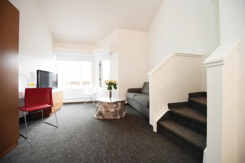 a living room with a couch and a tv and stairs at Elk + Avenue Hotel in Banff