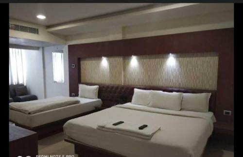 a hotel room with two beds and a chair at Hotel Adya Classsic in Kammasandra