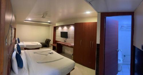 a small room with two beds and a bathroom at Hotel Adya Classsic in Kammasandra