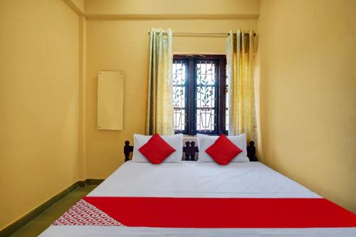 a bedroom with a bed with red pillows and a window at Hotel O Lekshmi Rooms & Villas in Alleppey