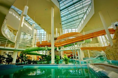a swimming pool with a water slide in a building at Máté apartman in Gyula