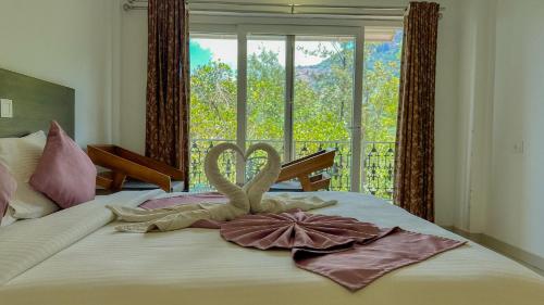 a bed with towel animals on it with a window at The Heights Munnar in Munnar