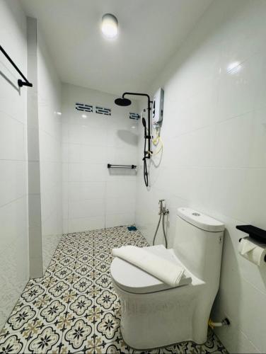 a white bathroom with a toilet and a tile floor at 1917 By MUO in Muar