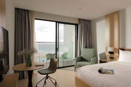 a hotel room with a bed and a desk and chair at The Cam Ranh Near The Airport in Cam Ranh International Airport