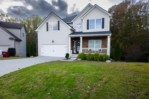 a white house with a garage and a grass yard at Large Rustic Family Home By RoadATL-KingBed-Firepit-Grill in Braselton