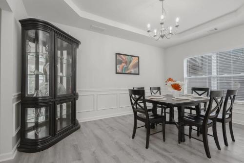 a dining room with a table and chairs and a chandelier at Large Rustic Family Home By RoadATL-KingBed-Firepit-Grill in Braselton