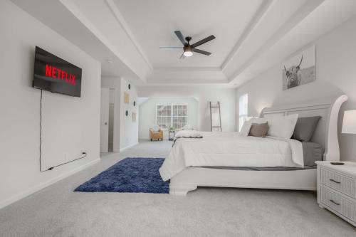 a white bedroom with a bed and a ceiling fan at Large Rustic Family Home By RoadATL-KingBed-Firepit-Grill in Braselton