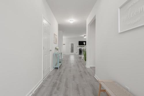 a hallway with white walls and a wooden floor at Large Rustic Family Home By RoadATL-KingBed-Firepit-Grill in Braselton